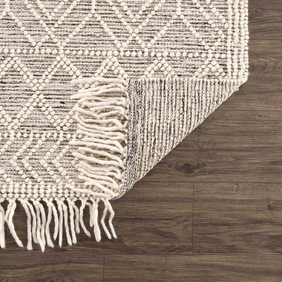 Hauteloom Ramsbury area rug with intricate geometric patterns in neutral tones, displayed folded on a studio background.