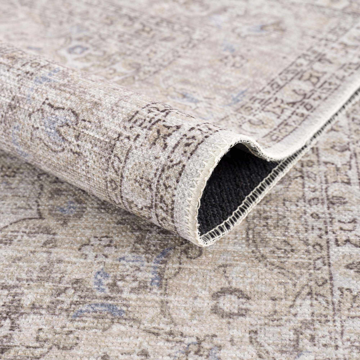 Folded Hauteloom Cream Holi-2301 washable area rug with intricate patterns, suitable for adding comfort to living spaces.