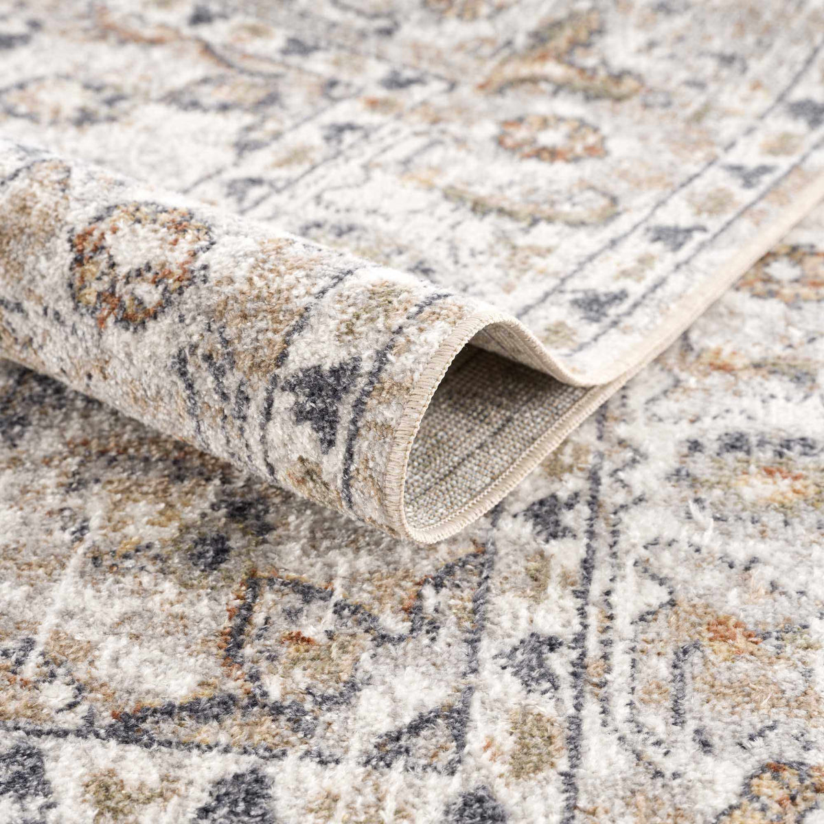 Cream Hiti washable area rug by Hauteloom, folded to show soft, plush texture and subtle cream color in a studio setting.