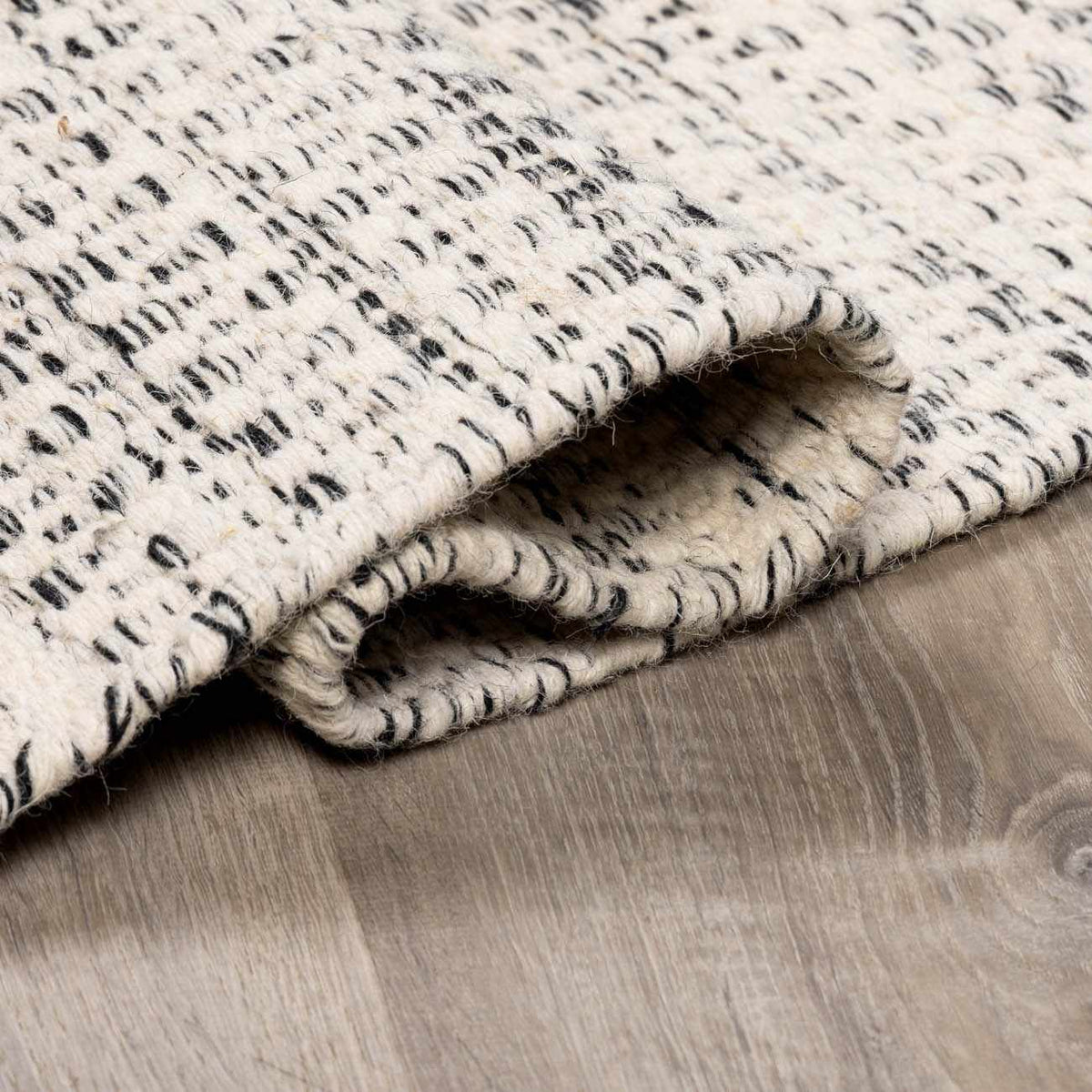 Williford Wool Area Rug by Hauteloom, folded display showing plush texture and intricate pattern in neutral tones.