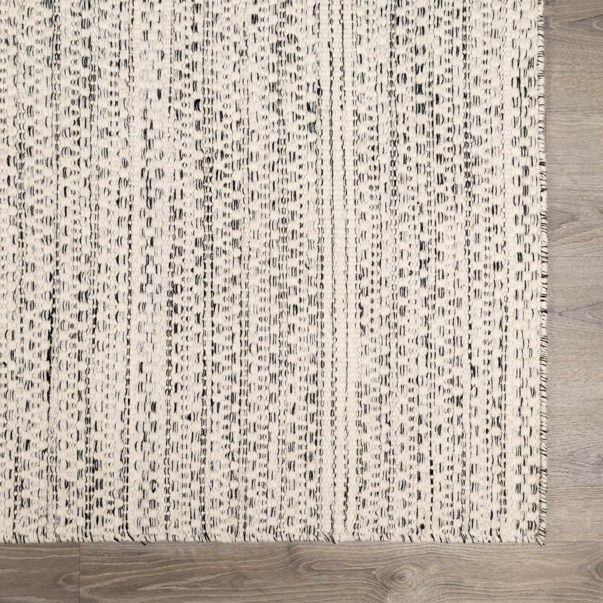 Williford Wool Area Rug by Hauteloom, close-up of textured wool fibers in earthy tones, showcasing intricate weaving details.