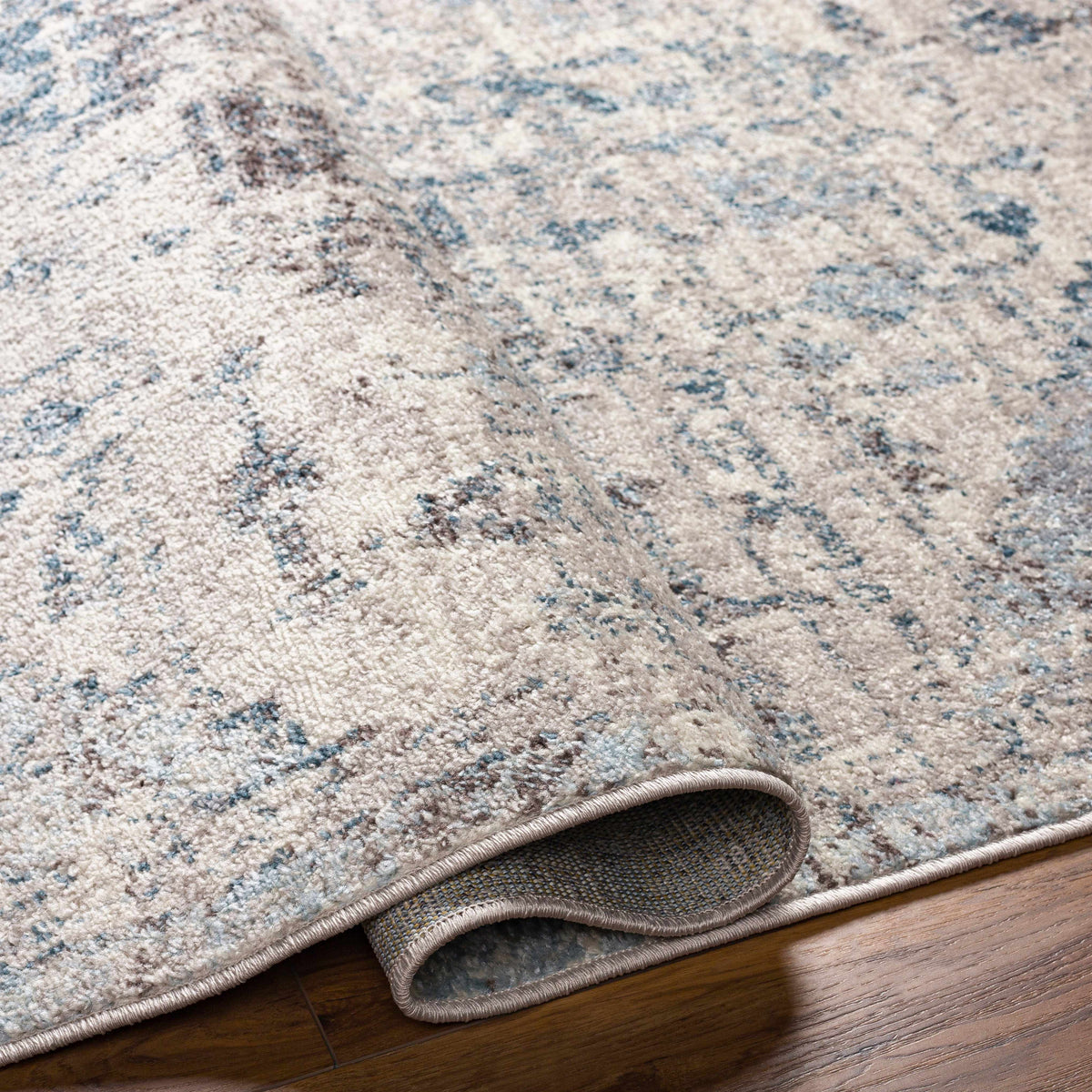 Hauteloom Orrick area rug with geometric pattern in neutral tones, shown folded on a light background, ideal for living room decor.